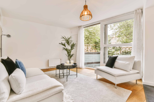 Bright modern living room with white furniture, large windows, and a potted plant