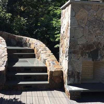 A stone wall with stairs leading up to a fireplace