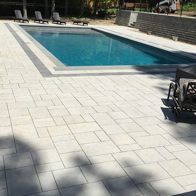 A large swimming pool surrounded by chairs and a brick wall