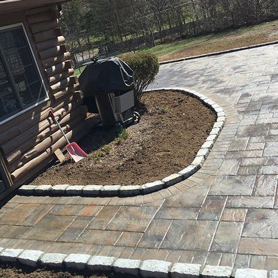 A brick walkway is being built in front of a log cabin.