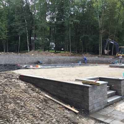 A large concrete wall is being built in the middle of a dirt field.