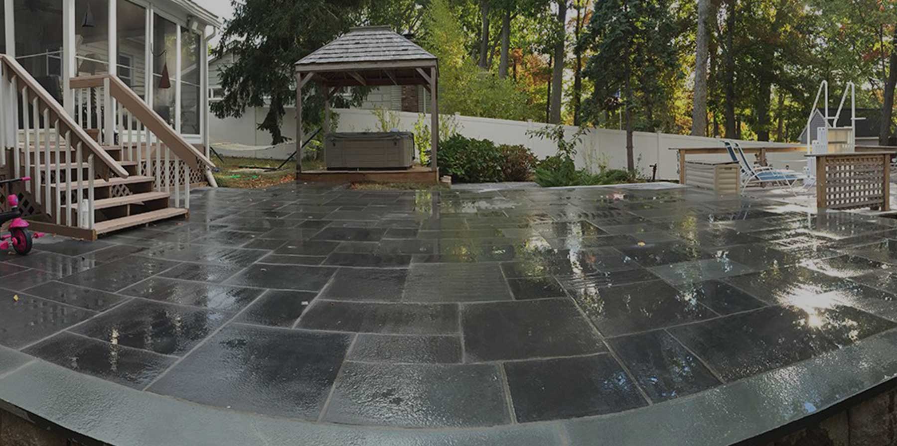 A large patio with a gazebo and stairs in the backyard.