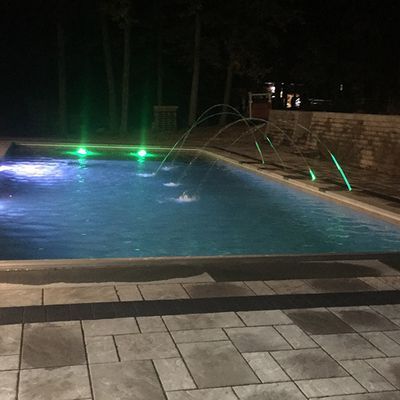 A large swimming pool is lit up at night with green lights.