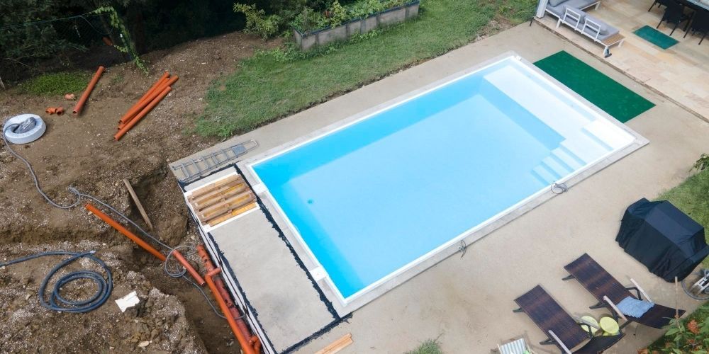 Aerial view of a backyard swimming pool with lounge chairs, umbrellas, and a patio area.