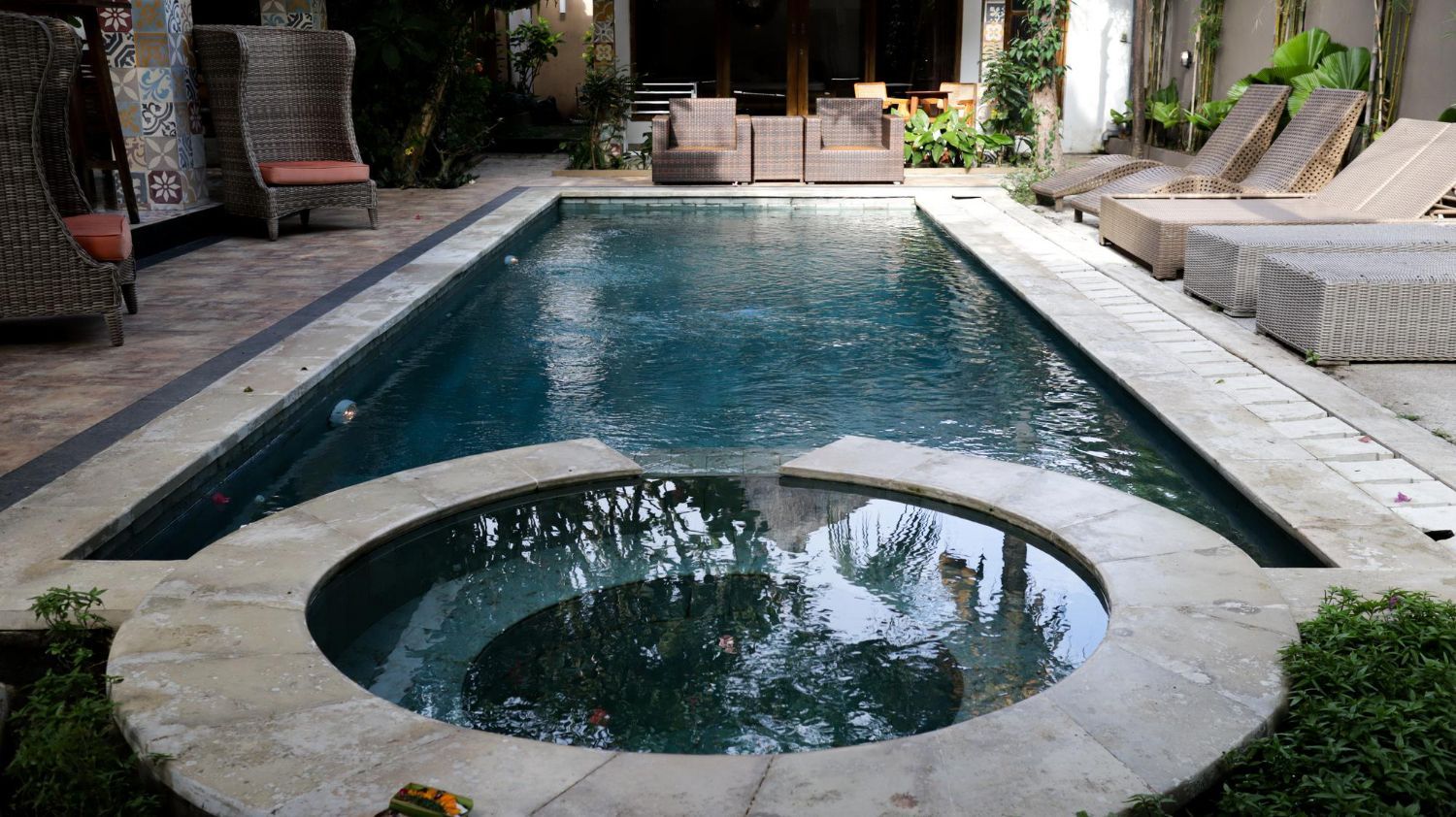 Courtyard pool with a circular spa at the near end, flanked by lounge chairs and greenery