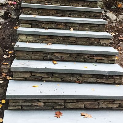A set of stone stairs leading up to a stone wall.