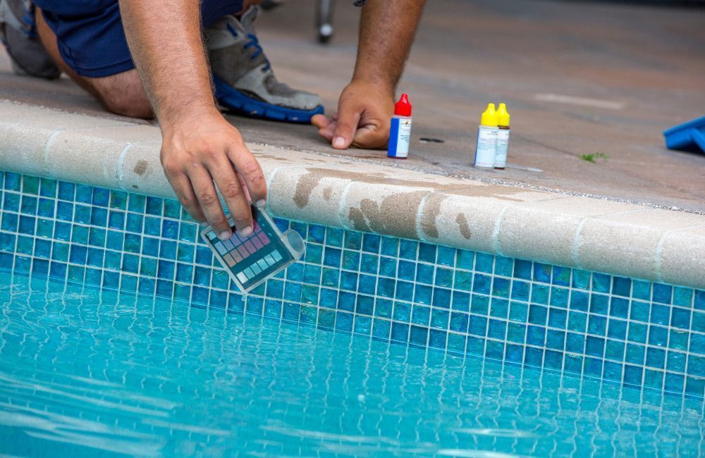 A man is testing the water in a swimming pool.
