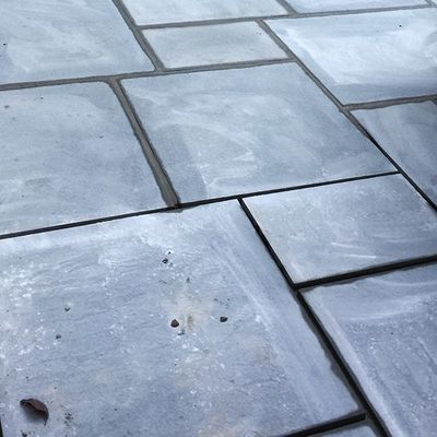 A close up of a gray tile floor with a leaf on it.