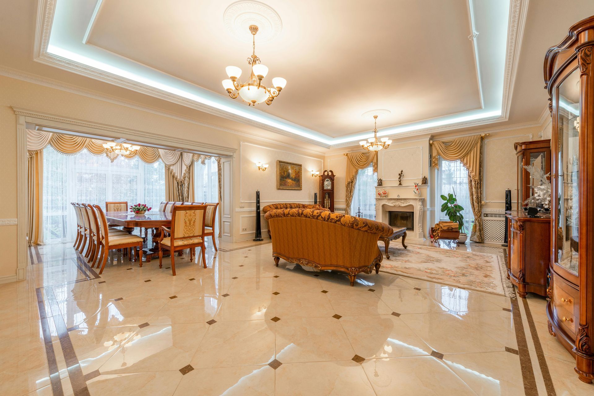 Luxurious living room with ornate furniture, fireplace, dining area, and chandelier.