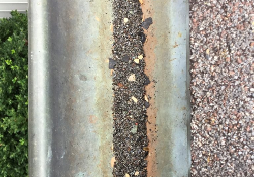 A metal gutter with a lot of rocks in it.