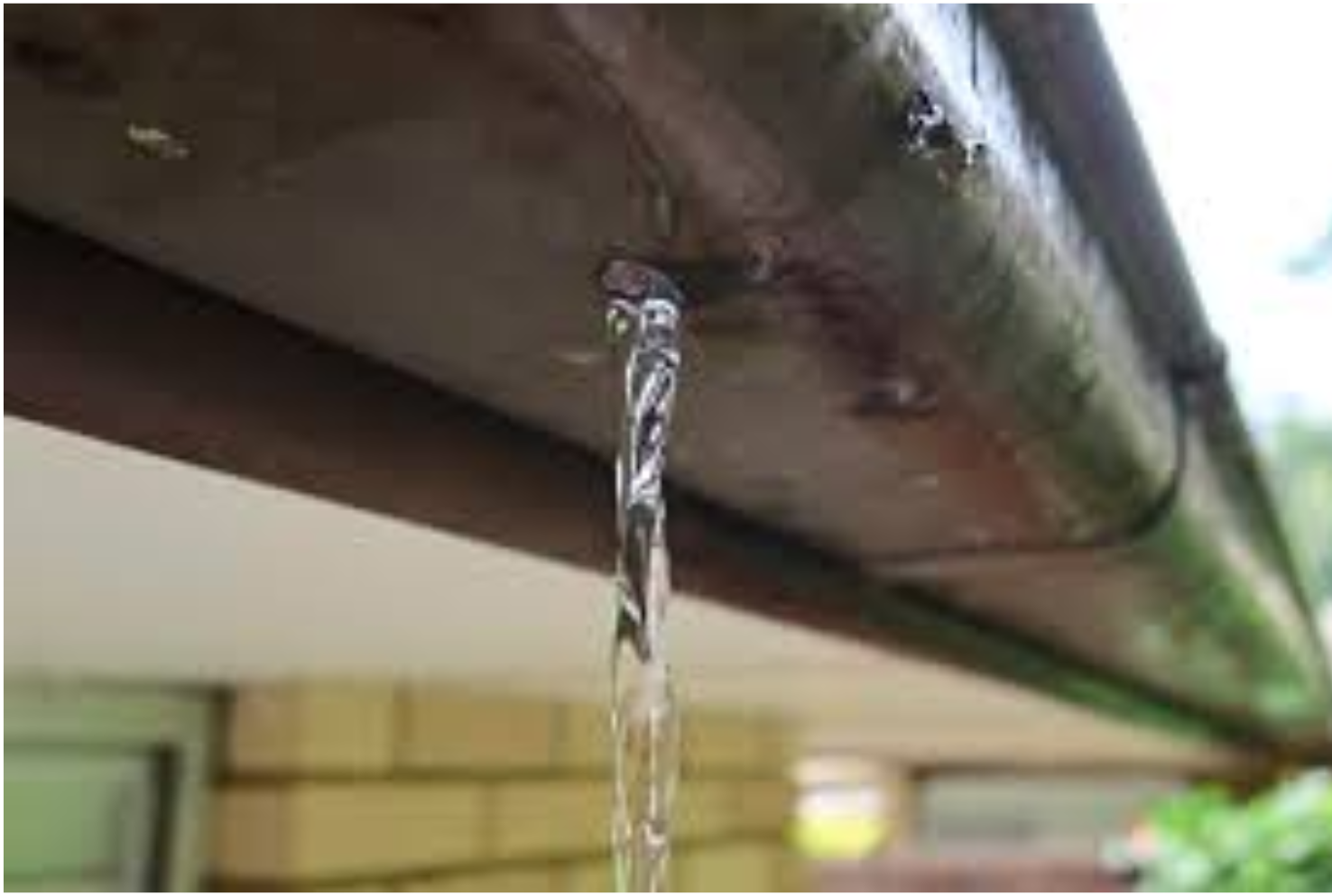 Water is dripping from a gutter on a house.