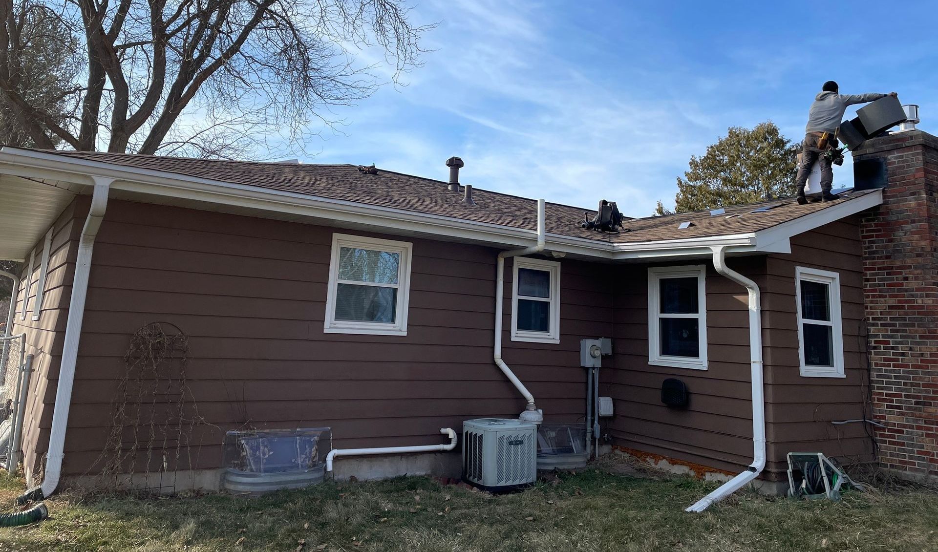 Two men are working on the roof of a house.
