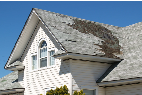 A white house with a roof that is missing shingles