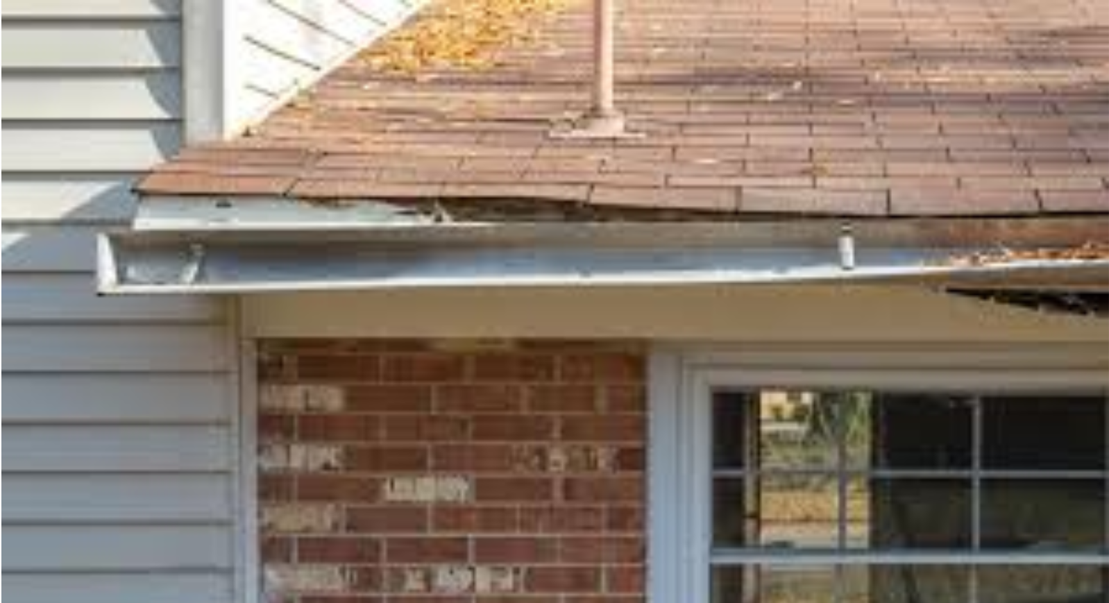 There is a twisted gutter on the side of a house with a window.