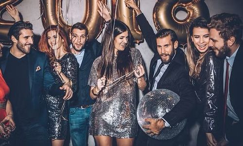 Group of people dressed up at a party, holding balloons and posing with drinks in a festive setting