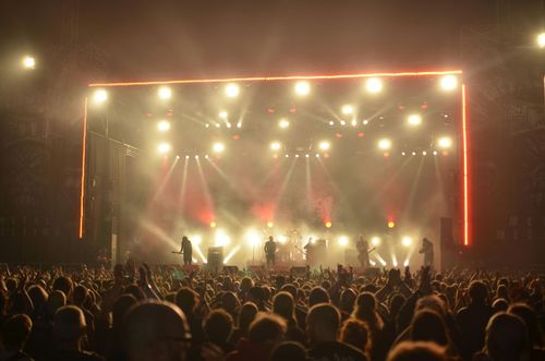 Crowded concert at night with bright stage lights and a glowing red frame around the stage