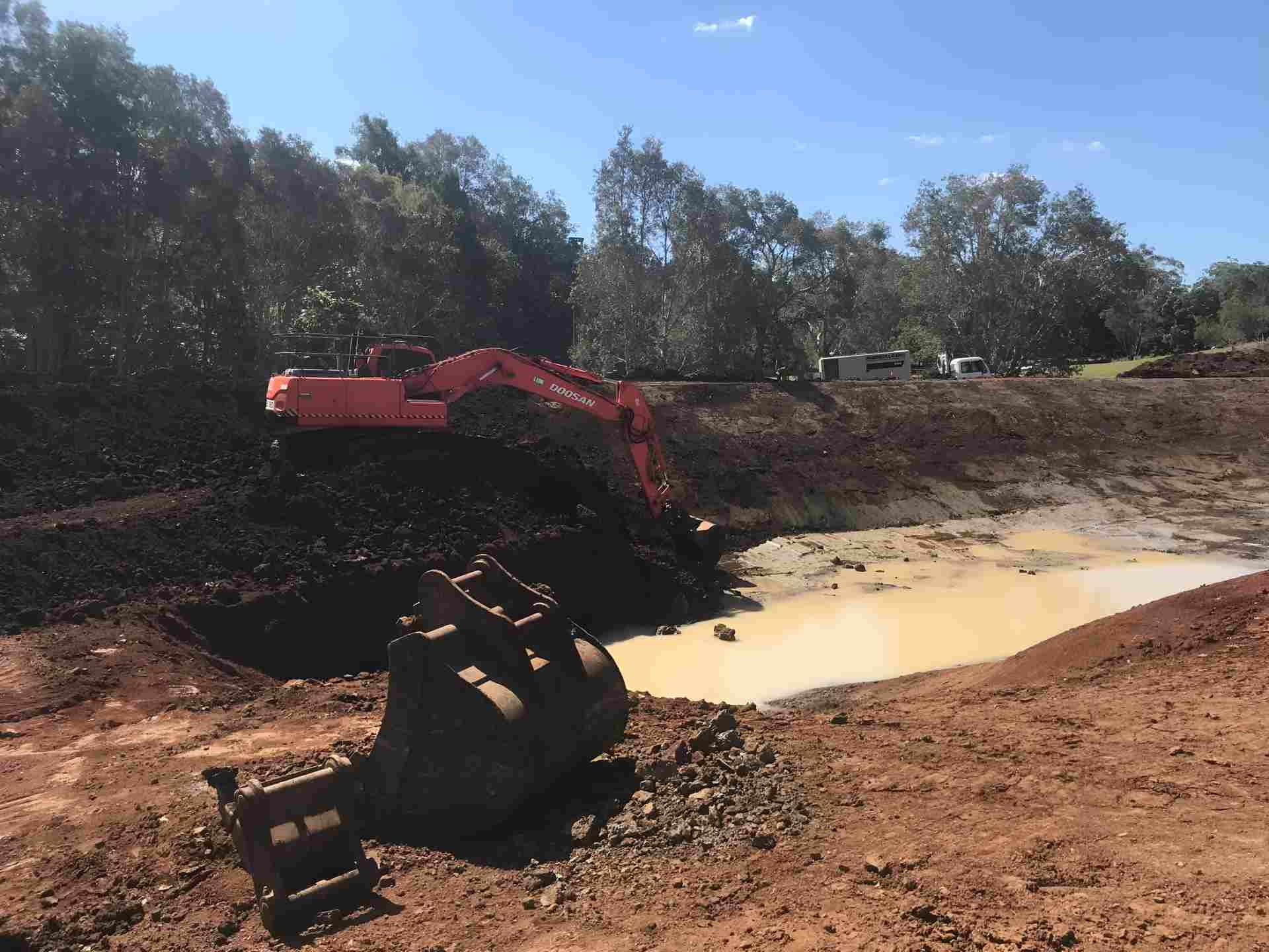 An Excavator is Digging a Hole in the Dirt Near a Pond — Eggins Earth & Road in Wardell, NSW