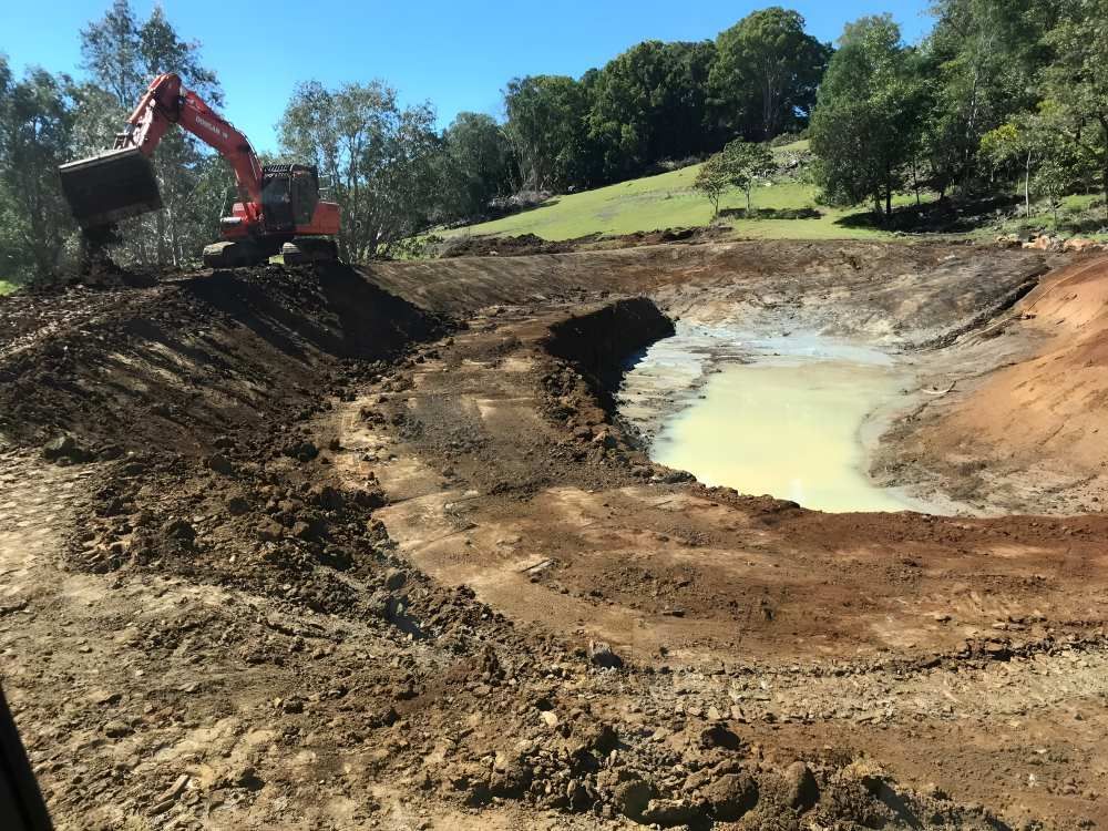 An Excavator is Digging a Hole in the Ground Near a Pond — Eggins Earth & Road in Ballina, NSW