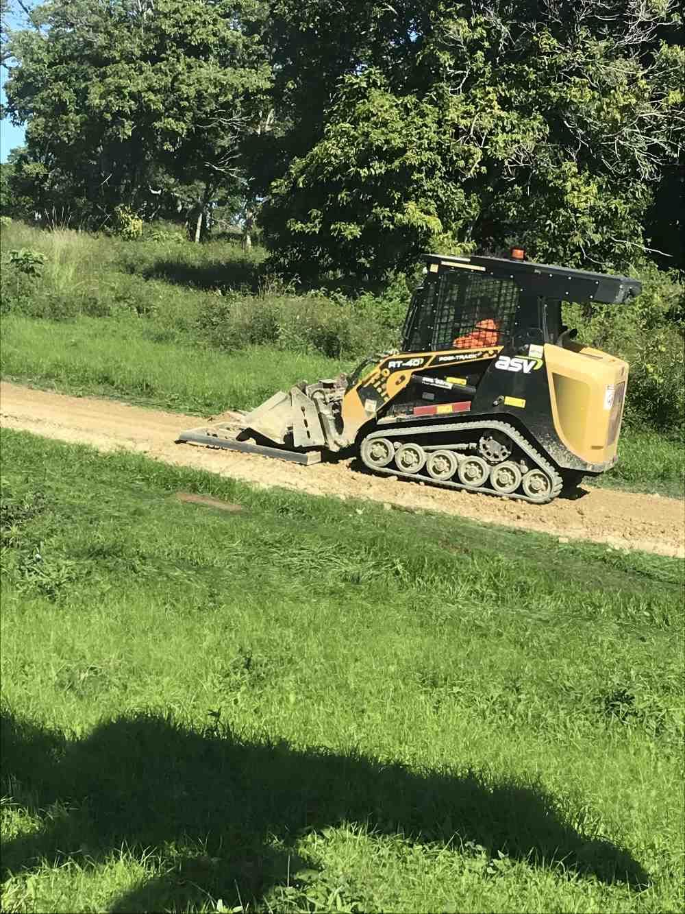 A Bulldozer is Driving Down a Dirt Road Next to a Grassy Field — Eggins Earth & Road in Wardell, NSW