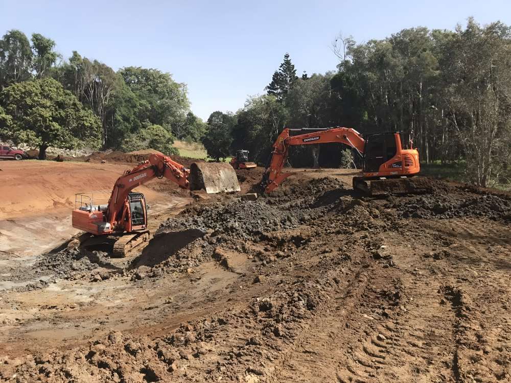 Two Excavators Are Working in a Muddy Field — Eggins Earth & Road in Wardell, NSW