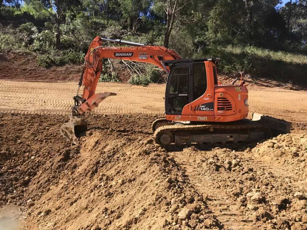 A Large Orange Excavator is Digging a Hole in the Dirt — Eggins Earth & Road in Wardell, NSW