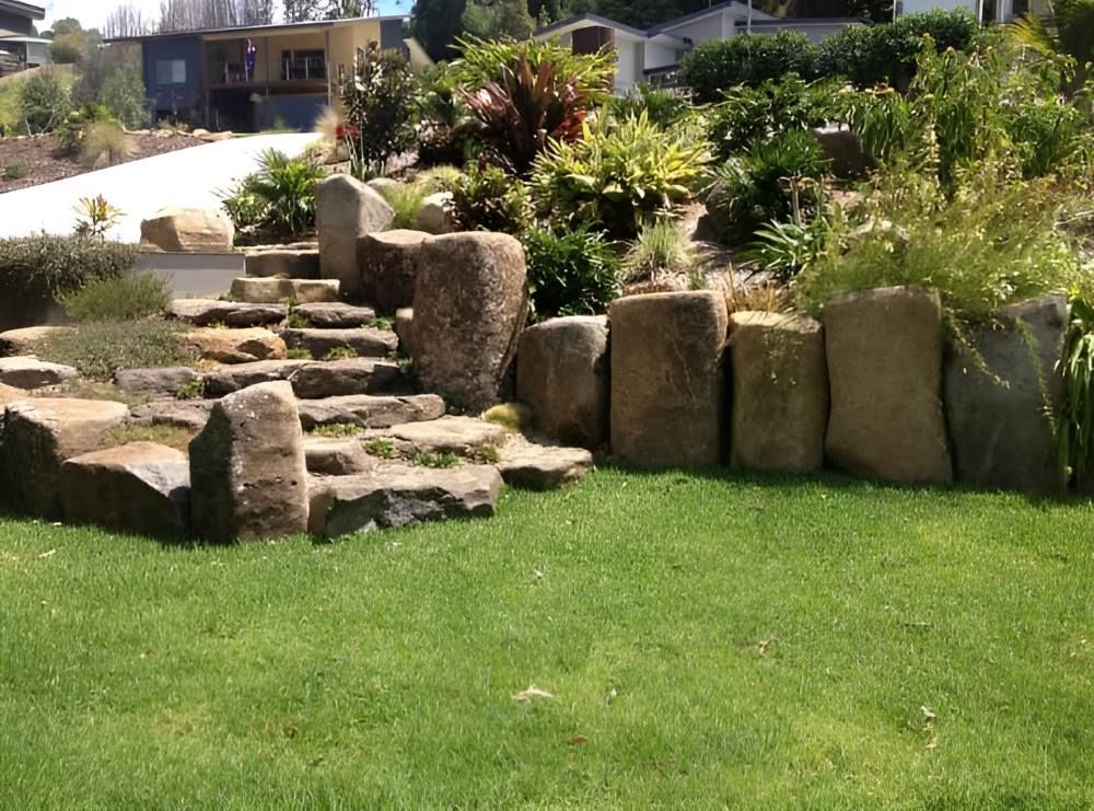 A Lush Green Lawn With a Stone Wall and Stairs — Eggins Earth & Road in Wardell, NSW
