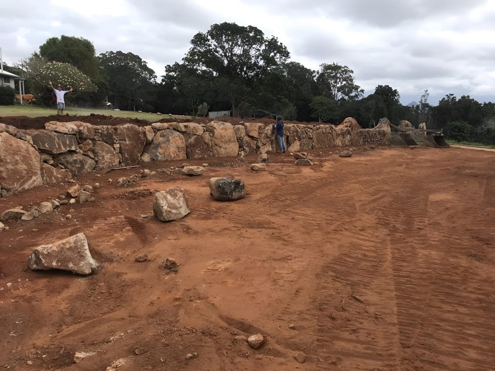 A Large Rock Wall is Being Built in a Dirt Field — Eggins Earth & Road in Wardell, NSW
