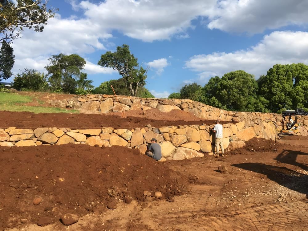 A Group of People Are Working on a Rock Wall in a Field — Eggins Earth & Road in Wardell, NSW