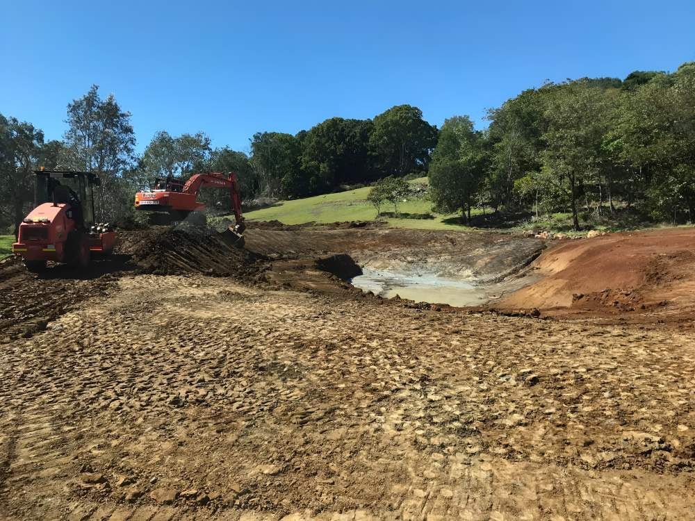 A Large Orange Excavator is Working on a Dirt Field — Eggins Earth & Road in Wardell, NSW