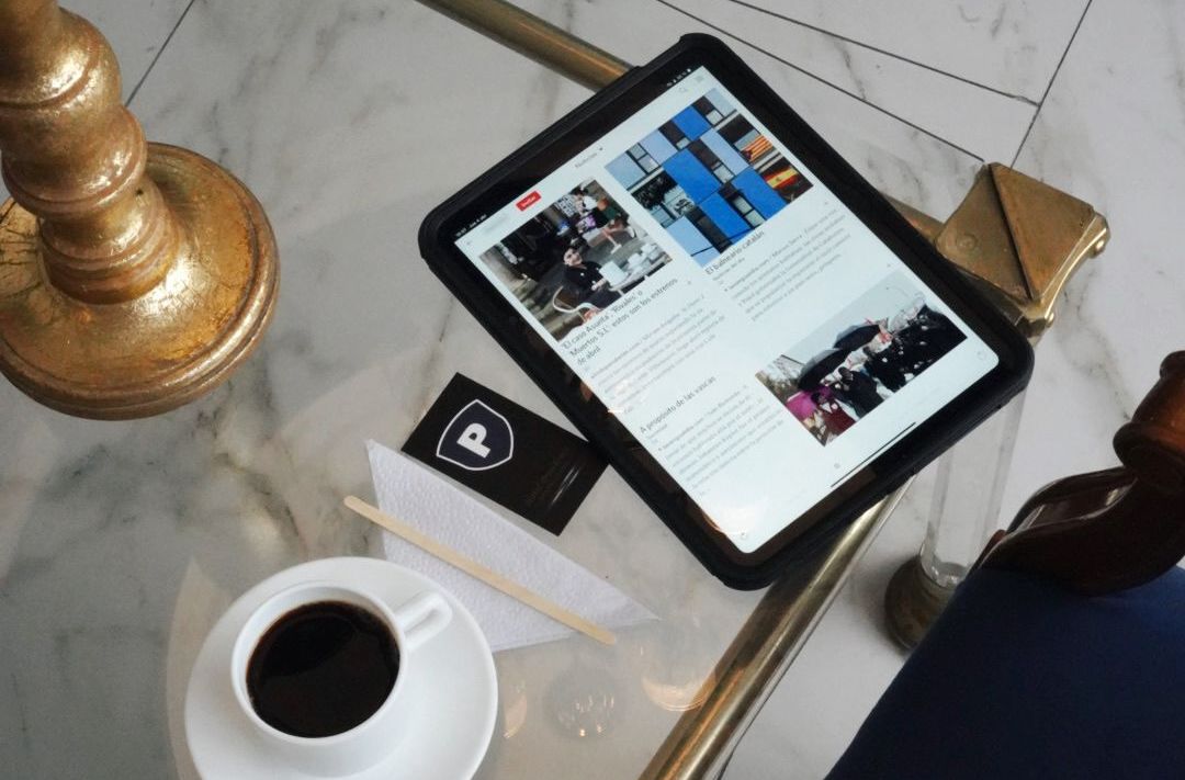 Hay una tableta sobre una mesa junto a una taza de café.