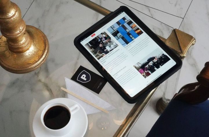 Hay una tableta sobre una mesa junto a una taza de café.
