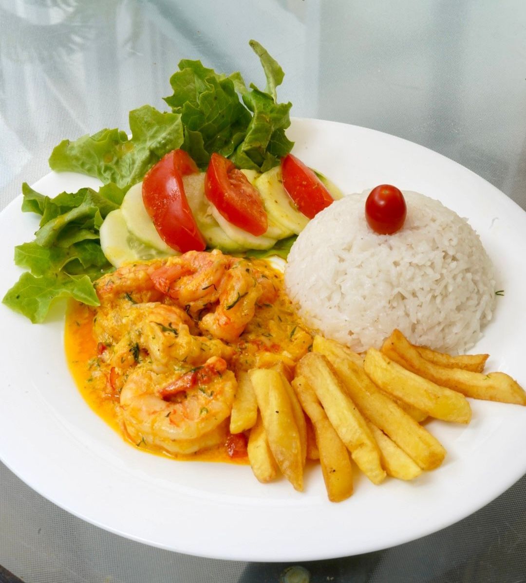 Un plato blanco cubierto con arroz con camarones y papas fritas.