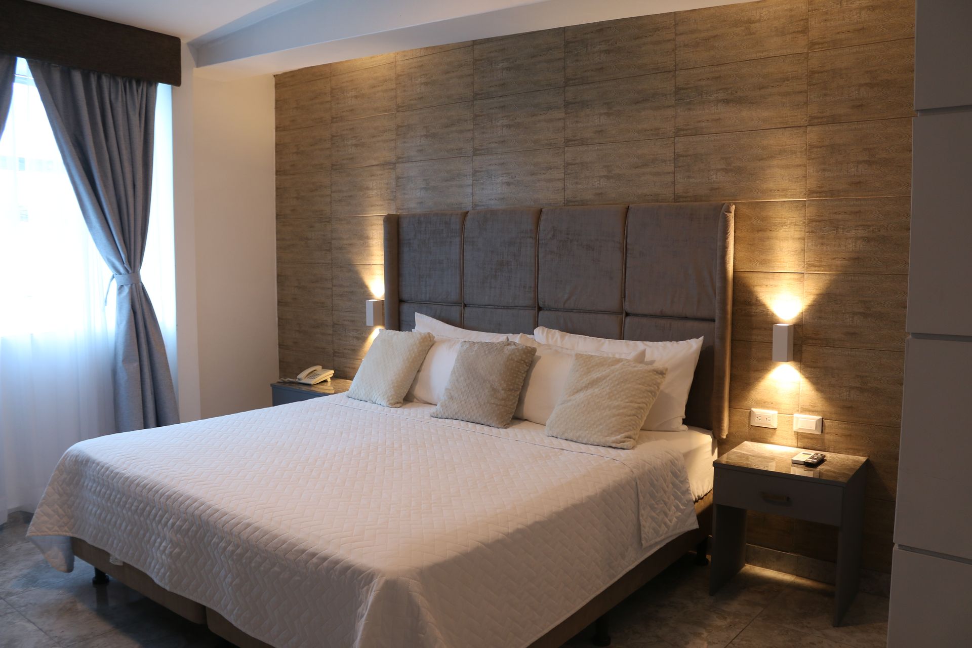 Una habitación de hotel con una cama tamaño king y dos mesitas de noche.