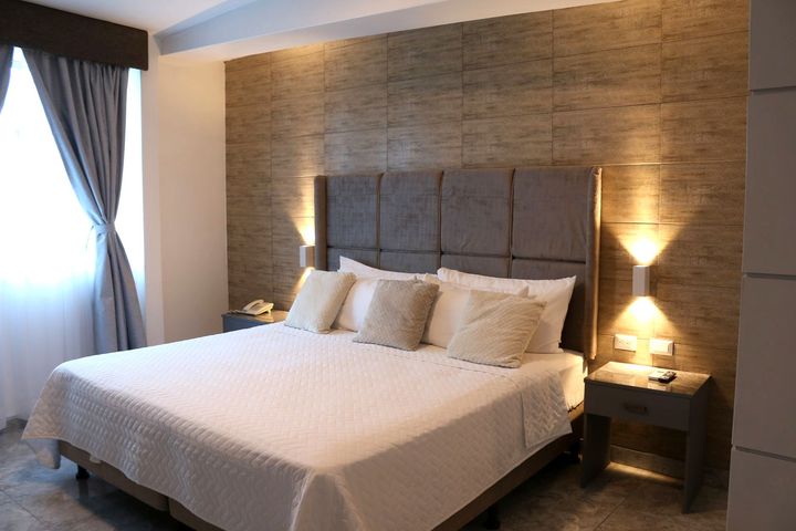 Una habitación de hotel con una cama tamaño king y dos mesitas de noche.