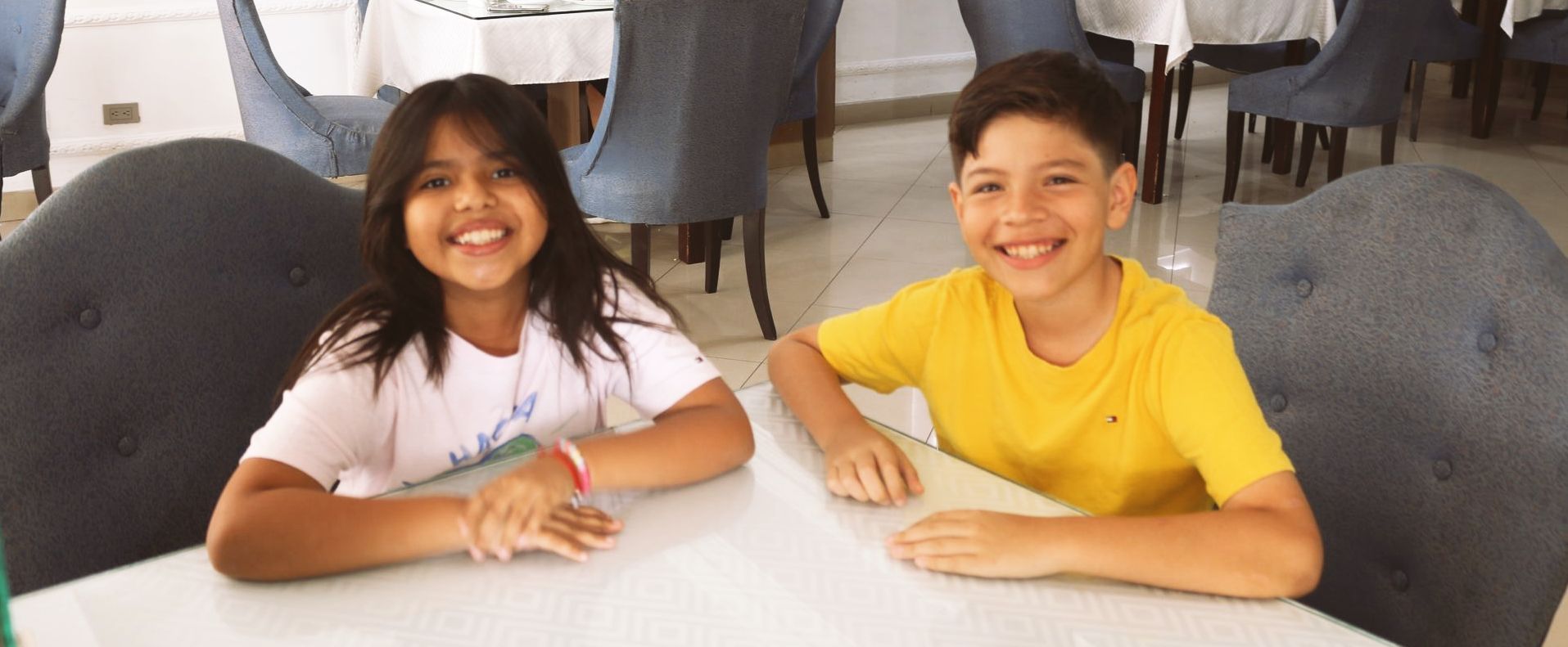 Un niño y una niña están sentados en una mesa en un restaurante.