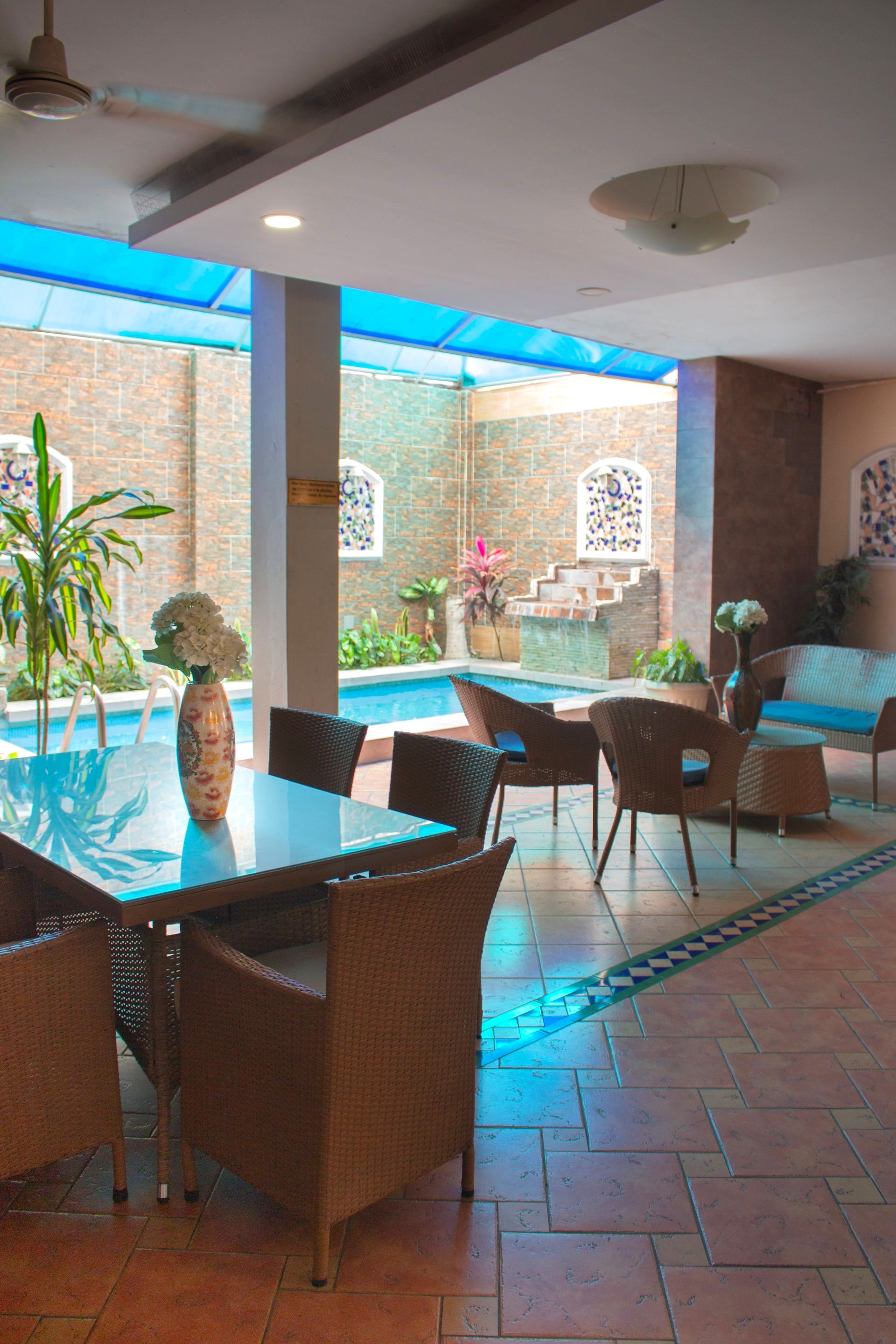 Una habitación con una mesa y sillas frente a una piscina.