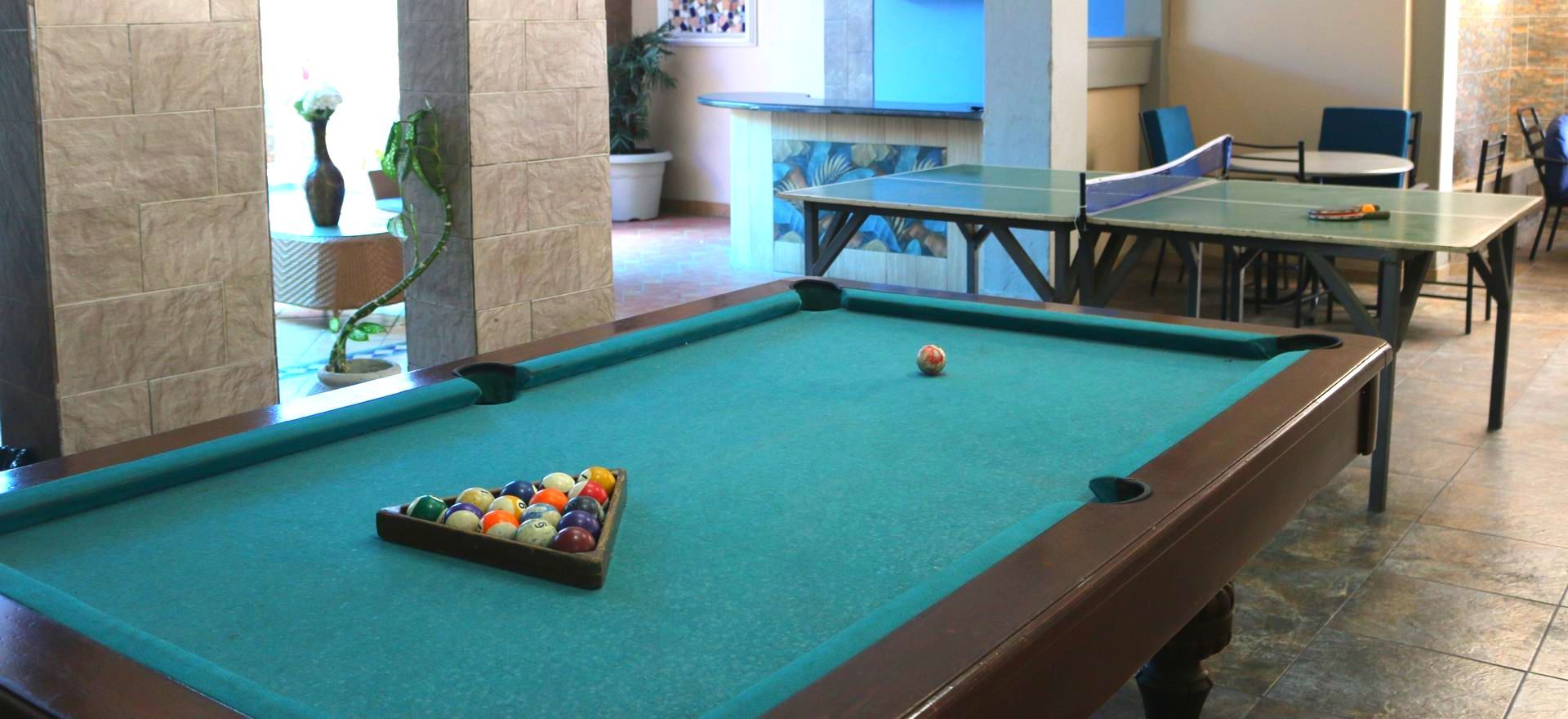 Una mesa de billar en una habitación con mesas de ping pong