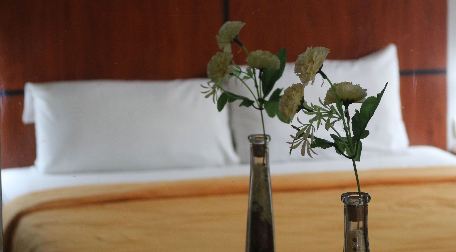 Dos jarrones con flores sobre una cama en una habitación de hotel.