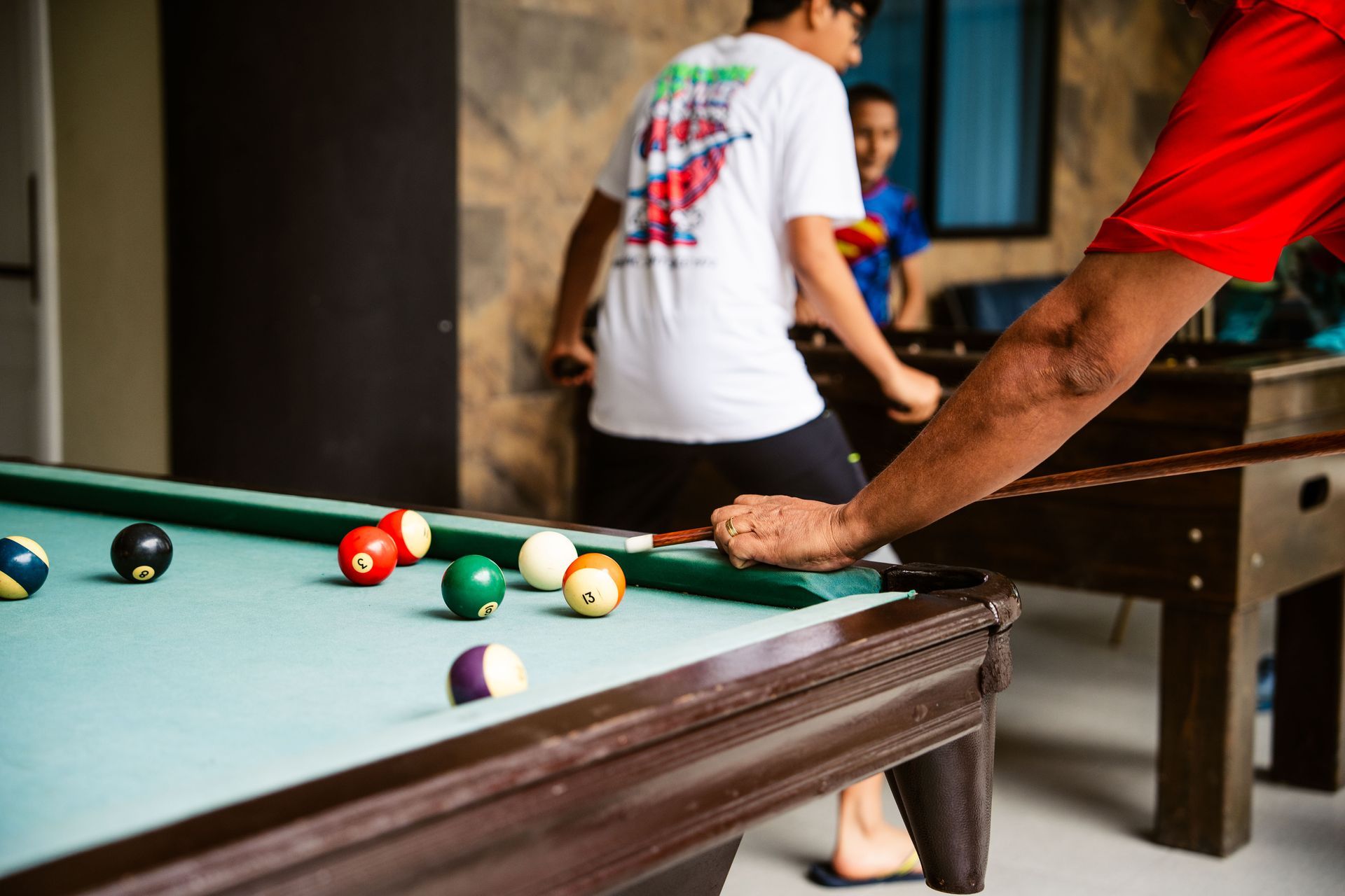 Un hombre está jugando al billar en una habitación con otras personas.