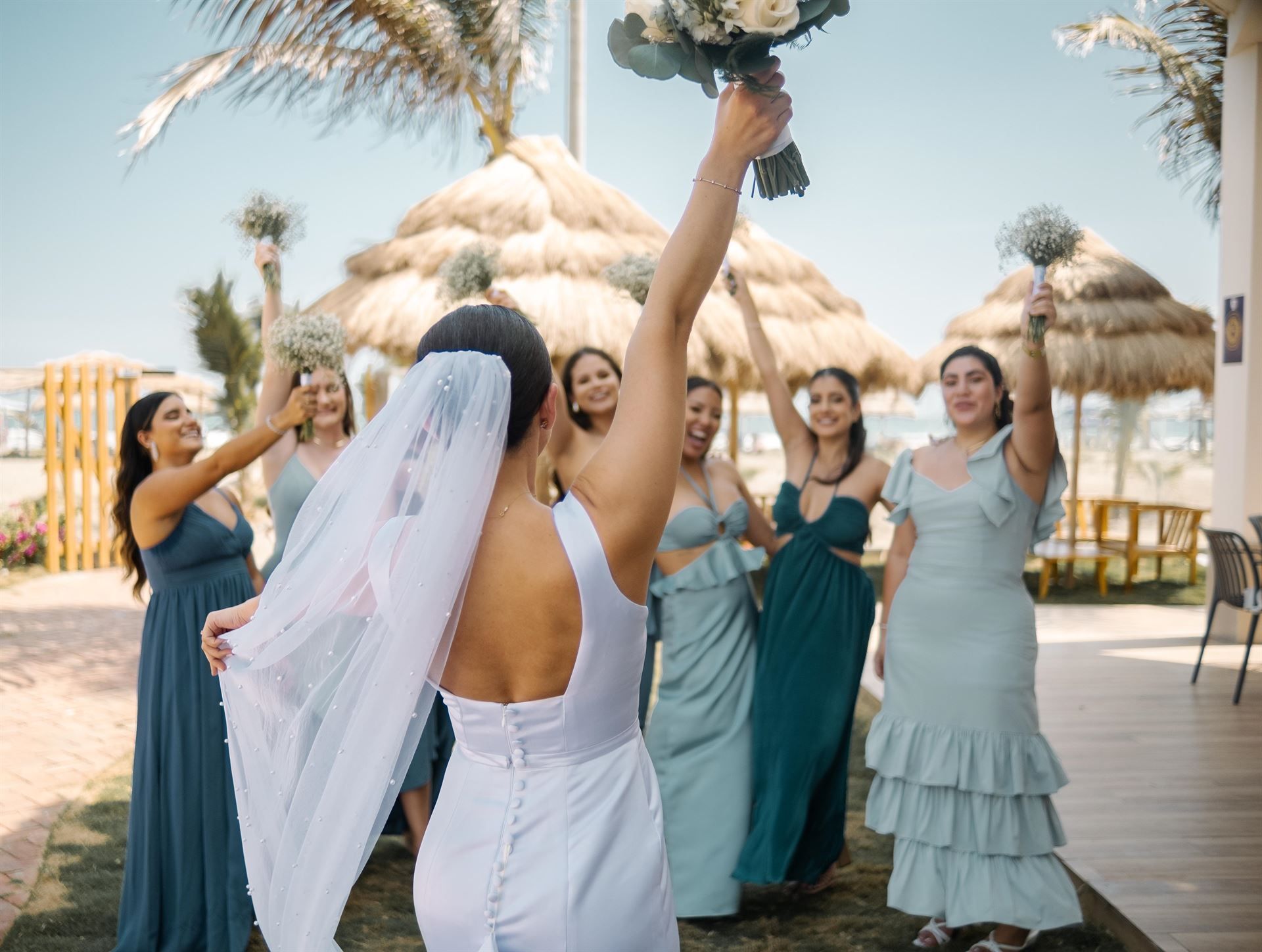 Una novia y sus damas de honor están lanzando un ramo de flores al aire.