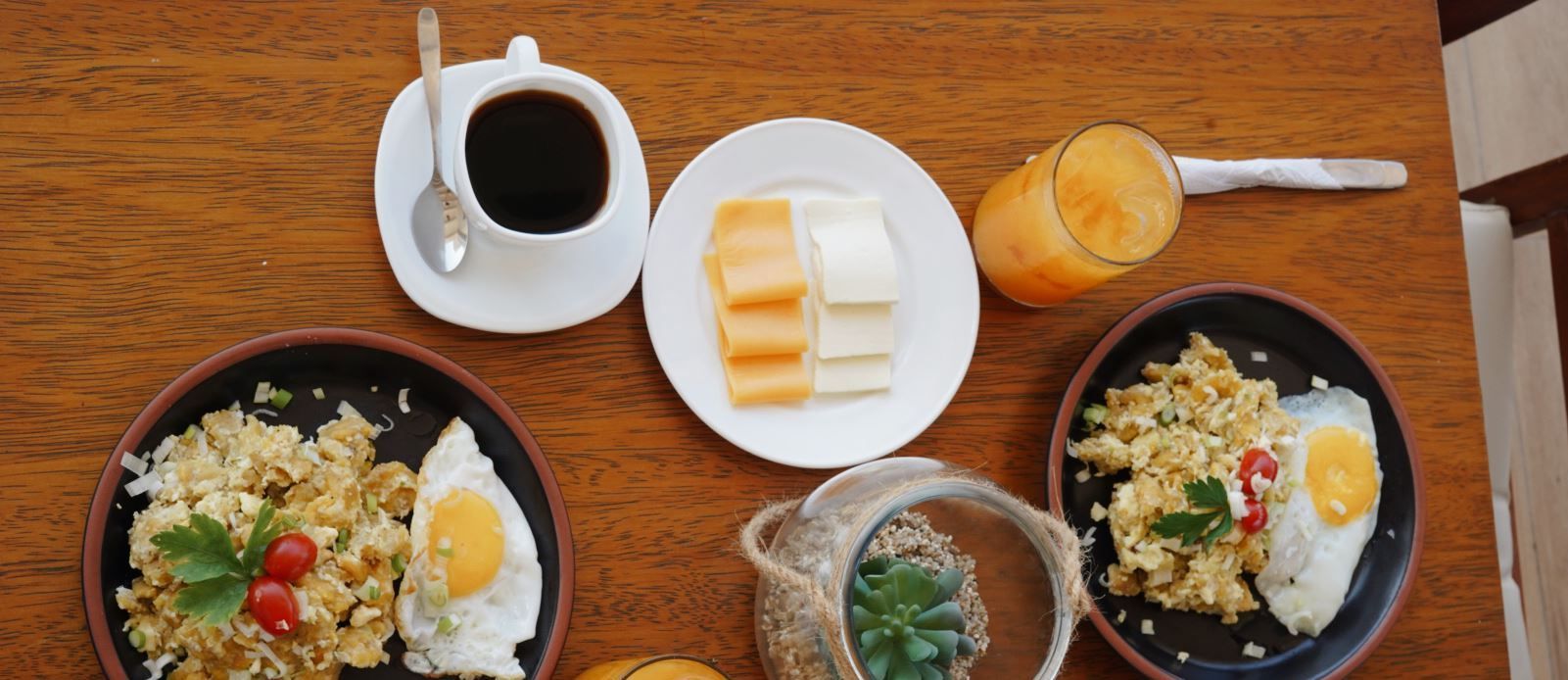 Una mesa de madera cubierta con platos de comida y una taza de café.