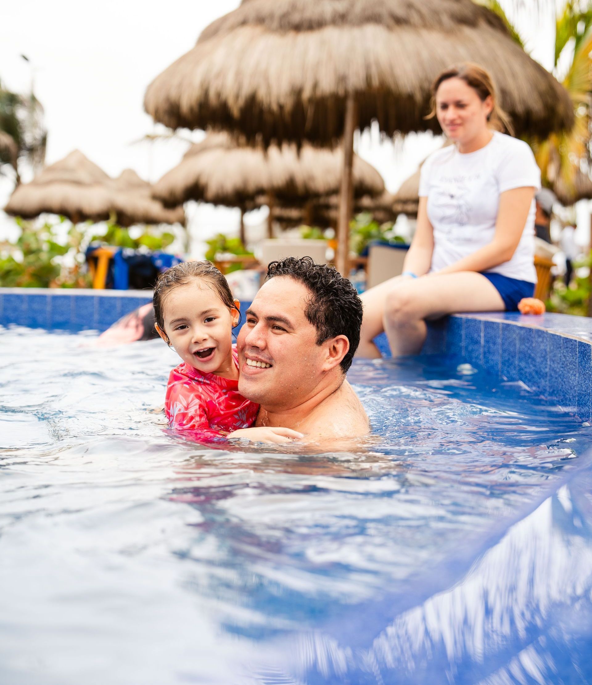 Un hombre y una niña están jugando en una piscina.