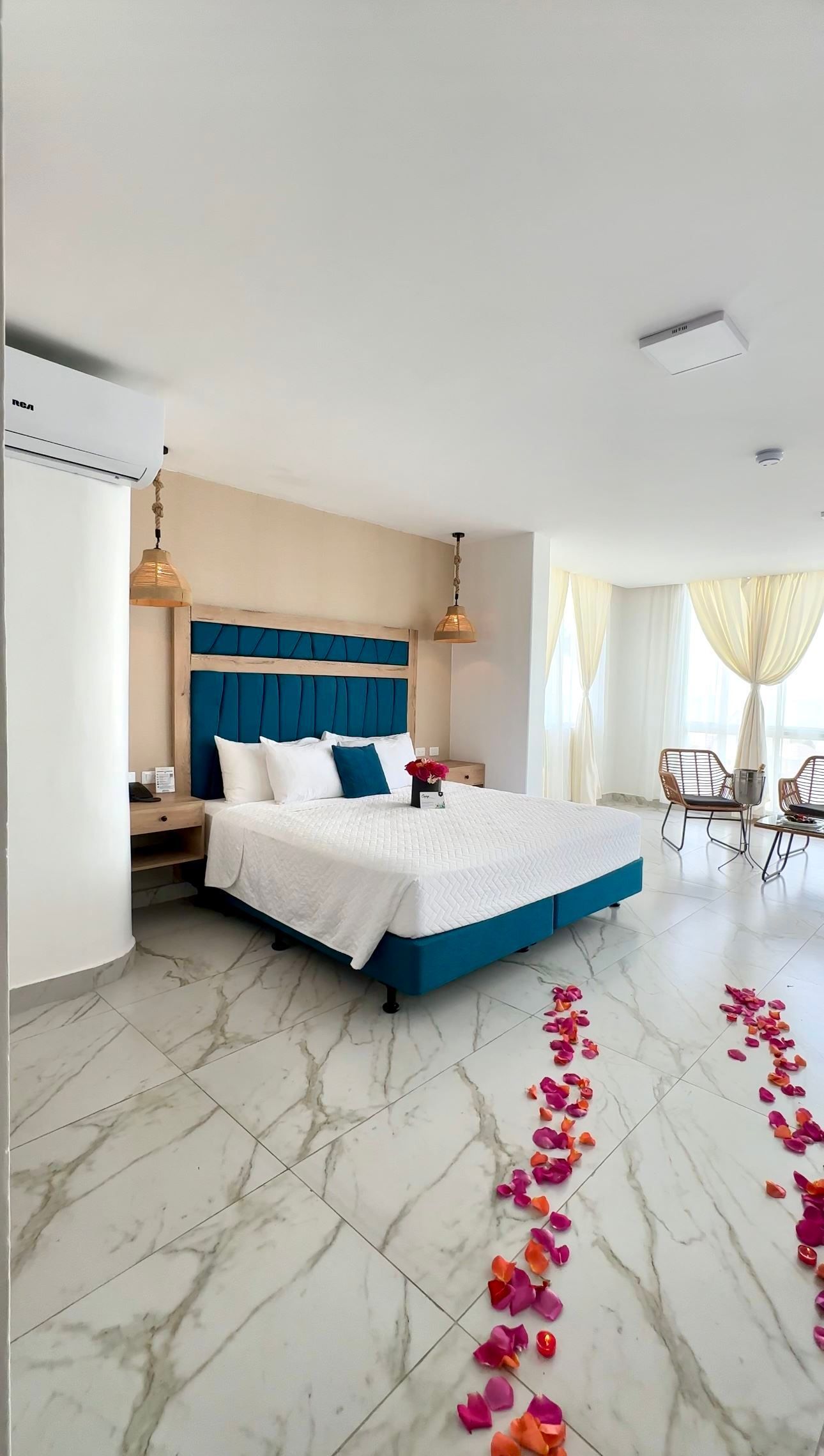 Una habitación de hotel con una cama tamaño king y pétalos en el suelo.