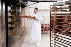 A man is holding a tray of cakes in a bakery. A man is holding a tray of cakes in a bakery.