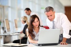 A man and a woman are looking at a laptop computer in an office. A man and a woman are looking at a laptop computer in an office.
