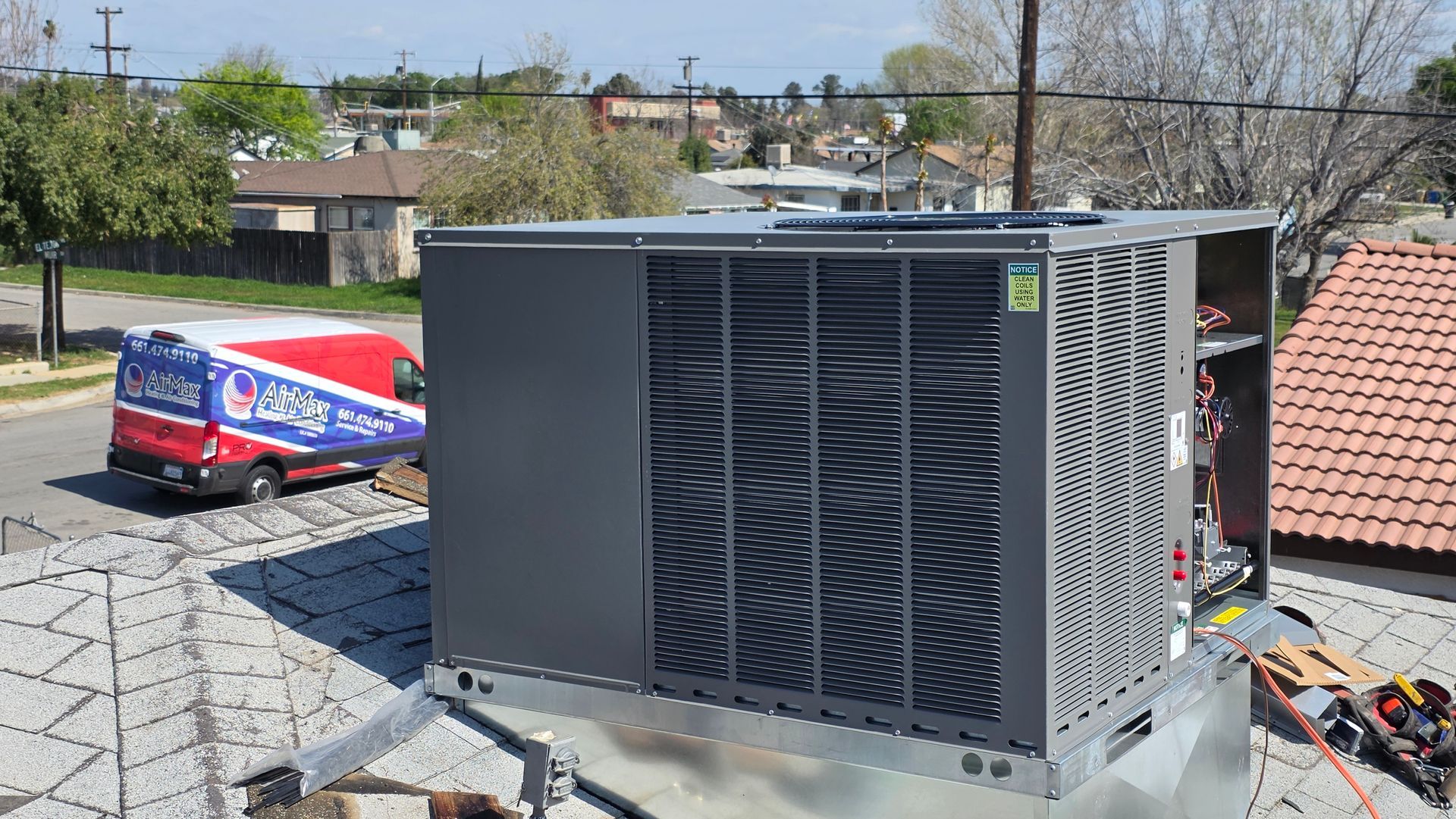 Technician inspecting outdoor air conditioner unit beside a house