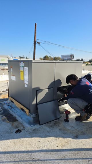 Technician connecting gauges to an outdoor air conditioner unit for maintenance