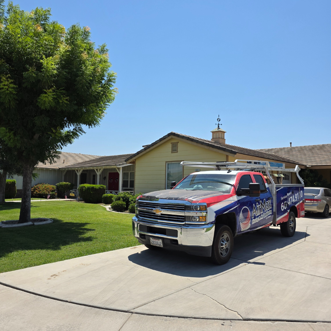 Red, white, and blue pickup truck parked in a sunny suburban driveway in front of a house