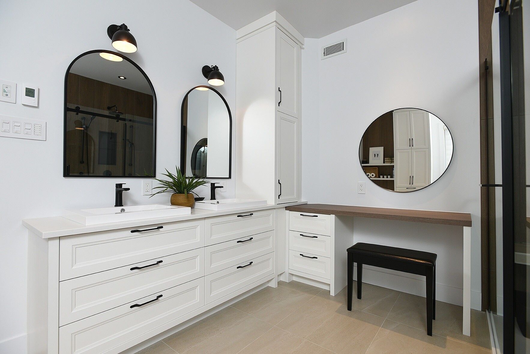 Une salle de bain avec deux lavabos, deux miroirs et un banc.