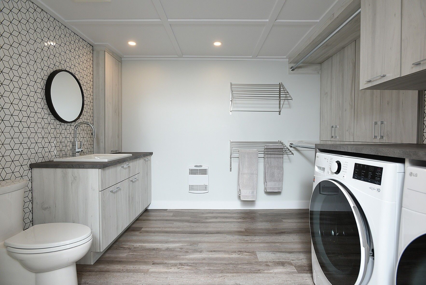 Une salle de bain avec toilette, lavabo, laveuse et sécheuse.